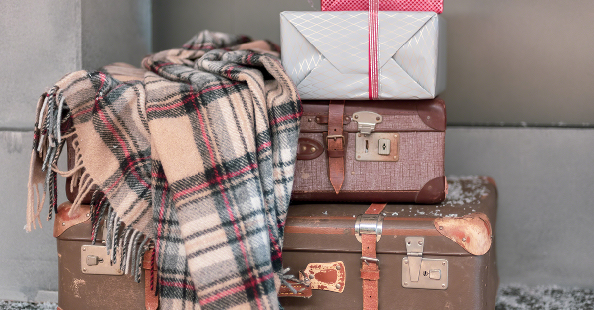 photo showing suitcases stacked, with wrapped Christmas presents on top, and a scarf draped over the suitcases